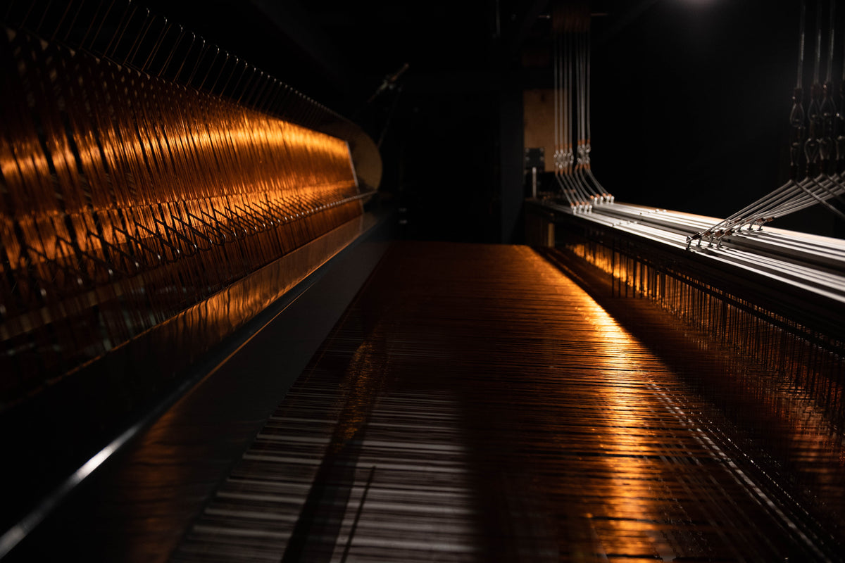 Close-up of VERDI's metal-thread weaving, copper filament interwoven with natural fiber on a manual loom